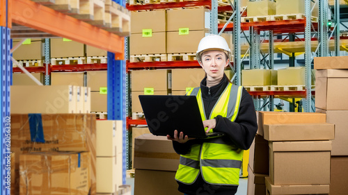 Warehouse woman. Supervisor with laptop. Storage specialist. Cardboard boxes around supervisor. Warehouse manager makes audit. Woman in storage building. Warehouse supervisor looking at camera