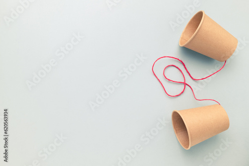 Paper cups phone with red string on empty clear background, two-way communication, talk to each other, media concept