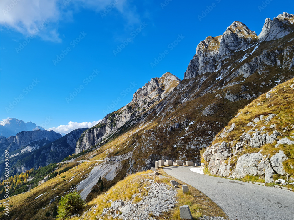 Obraz premium Alpine road over meadows under rocky peaks