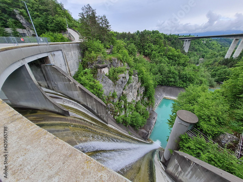 Water flowing over spillway of a hydroelectric dam, highway bridge in background photo