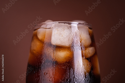 Cola with ice. Fresh cold sweet drink with ice cubes. Over brown background with copy space. Cola with ice. Fresh cold sweet drink with ice cubes.