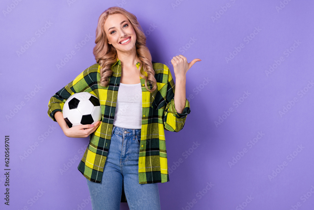 Photo of cute charming woman dressed checkered jacket holding ball pointing thumb empty space isolated purple color background Photo of cute charming woman dressed checkered jacket holding ball pointing thumb empty space isolated purple color background