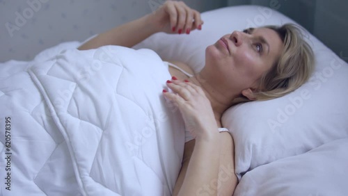 Exhausted woman lying in bed, suffering insomnia, jet lag or sleep disturbance during shift work, hot flashes during menopause