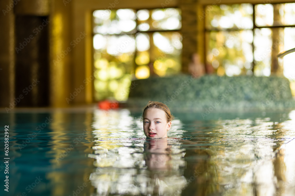 Cute young girl having fun in indoor pool. Child learning to swim. Kid having fun with water toys. Family fun in a pool. Cute young girl having fun in indoor pool. Child learning to swim. Kid having fun with water toys. Family fun in a pool.