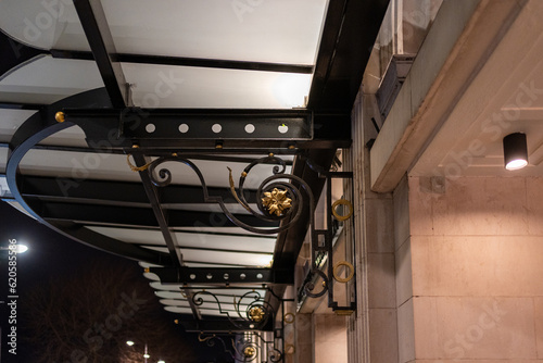 Old illuminated glass canopy at night with an ornate bracket