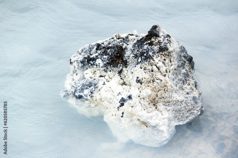 Black rock in milky white waters of Icelandic thermal nature baths near blue lagoon