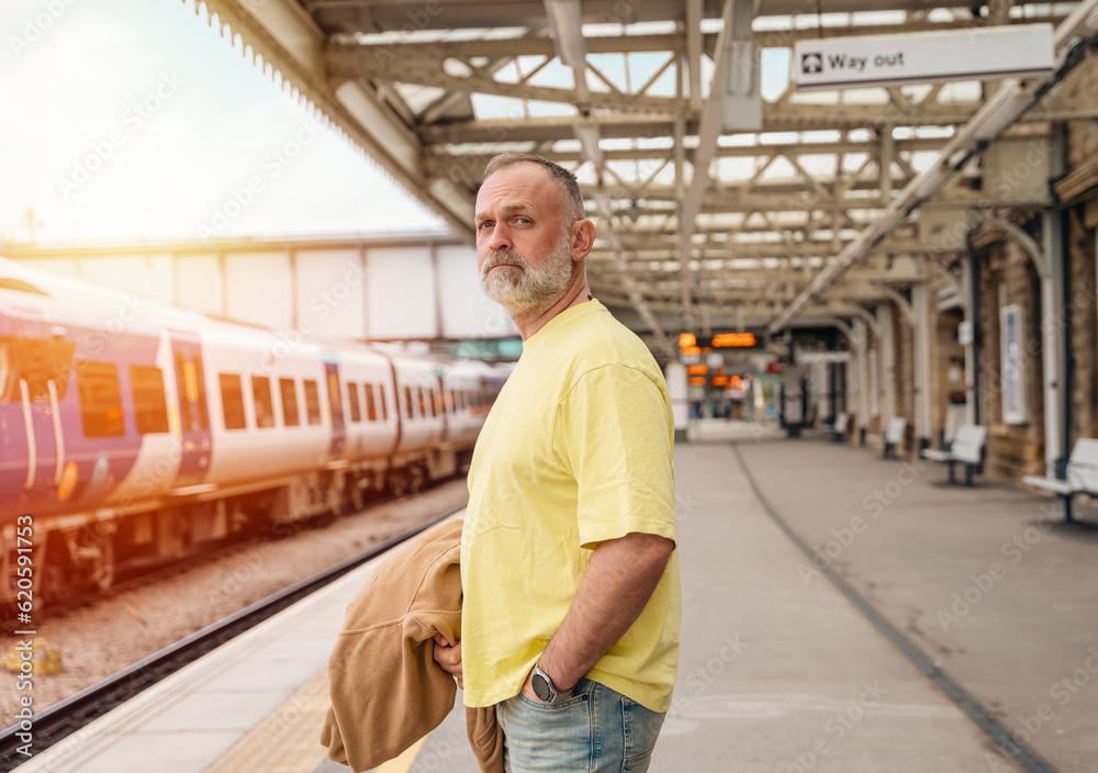 Traveler with a suitcase and  suit waiting for a train at the train station.   Travel concept.