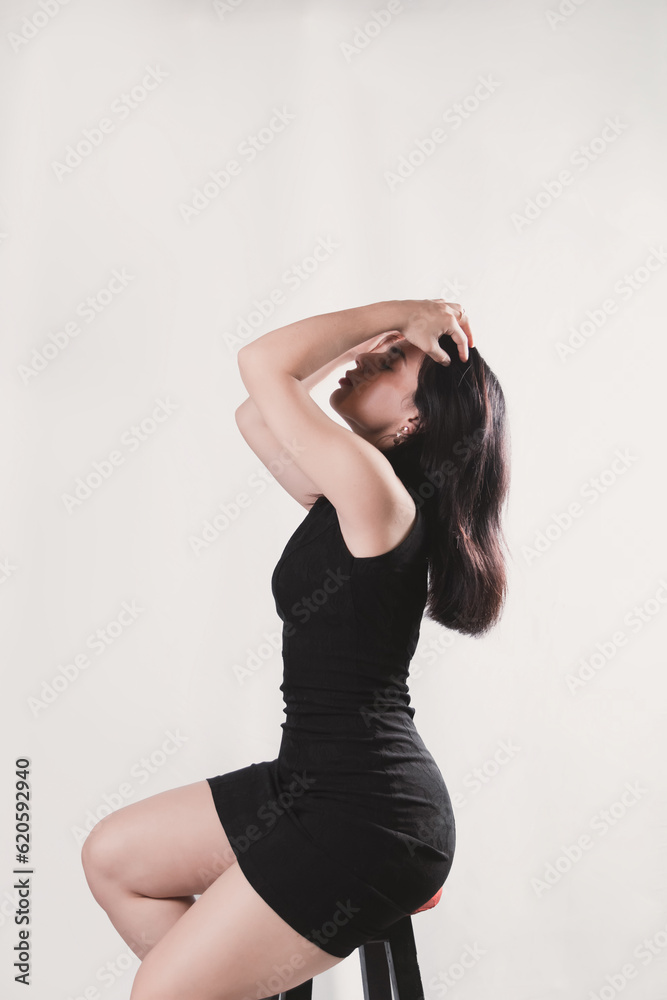 Elegant beautiful young woman in black dress sitting in an armchair sideways on a white background. Elegant beautiful young woman in black dress sitting in an armchair sideways on a white background.