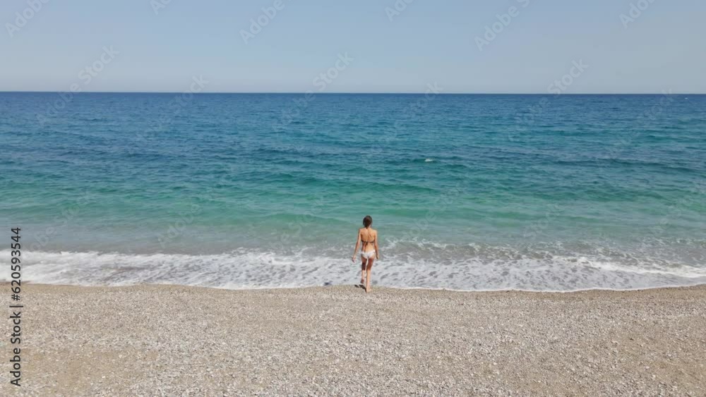 Aerial view of young woman in bikini swimsuit coming to sea for swimming in sea over coral reef. Happy island lifestyle. Vacation at Paradise. Ocean relax, travel to Turkey Aerial view of young woman in bikini swimsuit coming to sea for swimming in sea over coral reef. Happy island lifestyle. Vacation at Paradise. Ocean relax, travel to Turkey