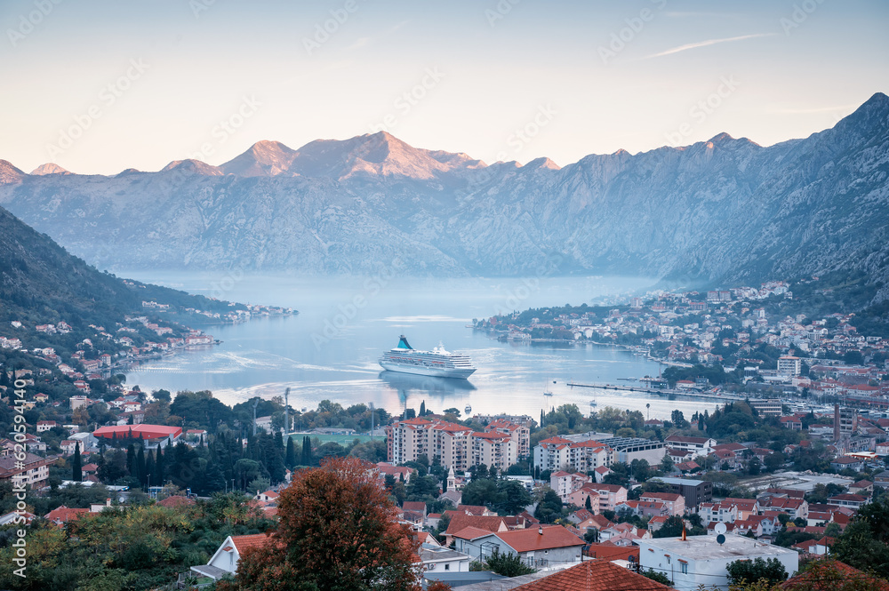 Amazing morning view of picturesque Kotor bay with old town and cruise ship entering the port..