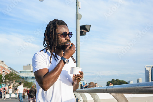 African man with beard dreadlocks walking and eating ice cream enjoying the day in Buenos Aires