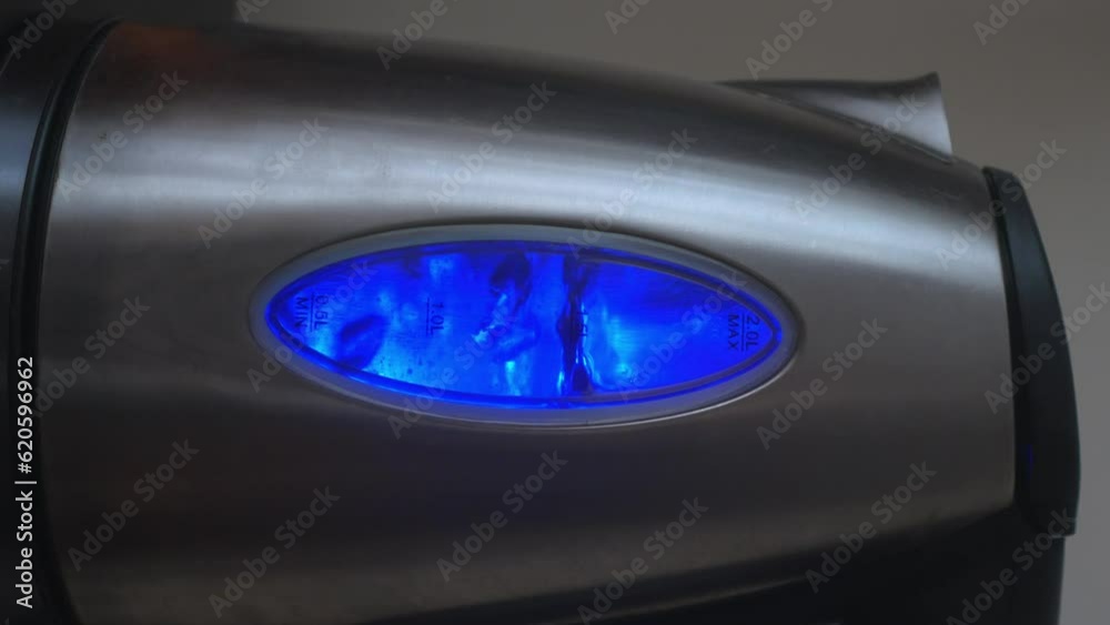 Vertical video of electric kettle with boiling water in neon blue lighting. Kettle is boiling in kitchen in dark room. Preparation of hot water or boiling water for coffee or tea. Vertical video of electric kettle with boiling water in neon blue lighting. Kettle is boiling in kitchen in dark room. Preparation of hot water or boiling water for coffee or tea.