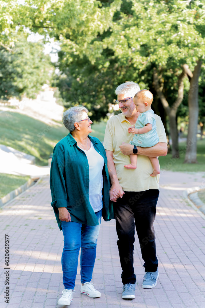 Grandparents walking in the park with their baby grandson Grandparents walking in the park with their baby grandson
