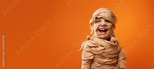 Cute Boy Dressed as a Mummy for Halloween on an Orange Banner with Space for Copy photo