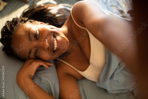 Young woman having a selfie while waking up in the bed in the bedroom