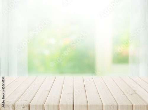 Selective focus.Wood table top on blur of window with garden flower background in morning.
