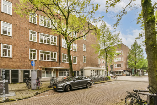 Photography a city street with parked cars and bicycles on the sidewalk in front of an apart