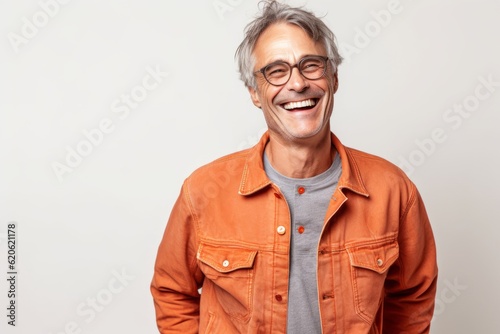 Foto Portrait of a smiling senior man in orange jacket and glasses on white backgroun