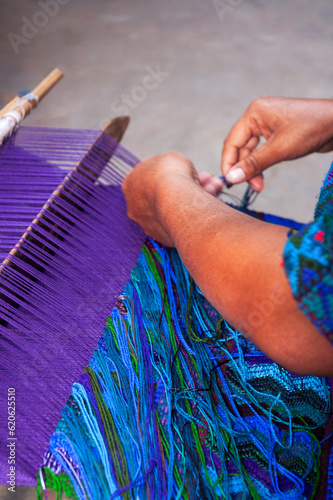 Detail of woman's hands weaving typical dyed cotton clothes in Guatemala, making clothes as a means of income from tourism.