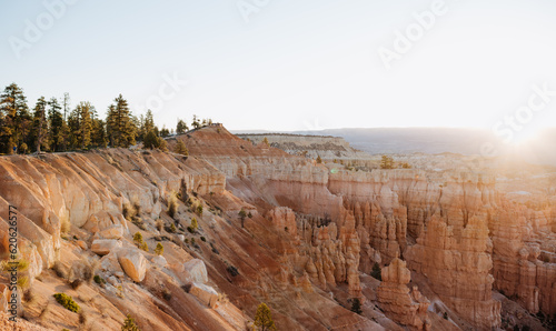 Bryce Canyon at first light, view from rim trail at Sunrise Point into canyon, contre-jour shot into sun with lens flares and copy space