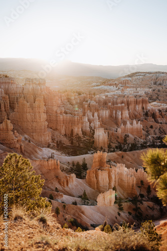 Bryce Canyon at first light, view from rim trail at Sunrise Point into canyon, contre-jour shot into sun with lens flares and copy space