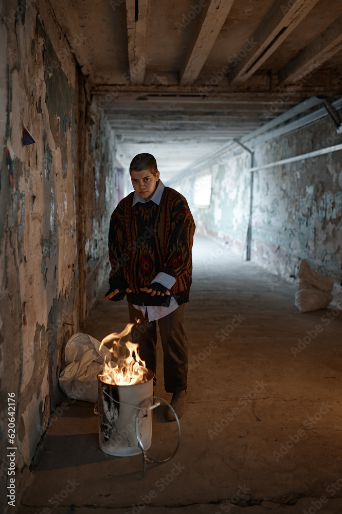 Lonely woman beggar warming hands by fire at night in tunnel