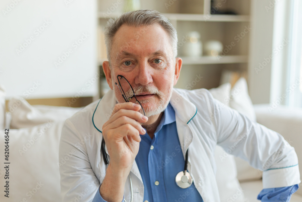 Mature senior male doctor in glasses medical uniform smiling looking at camera in hospital. General practitioner GP therapist professional healthcare expert in clinic. Healthcare concept Mature senior male doctor in glasses medical uniform smiling looking at camera in hospital. General practitioner GP therapist professional healthcare expert in clinic. Healthcare concept