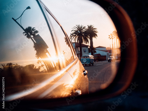 Rear view shot in car mirror with reflection of vintage van and palm trees at sunset in San Clemente, California, USA, flim look with lens flares and grain, lifestyle shot for cover