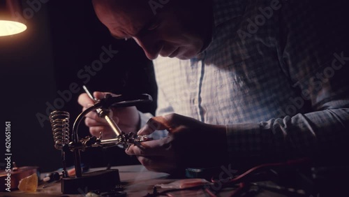 Repairing a microcircuit, smoke from soldering iron.Disconnect radio components.Scheme with precious metal, gold.Man solders Transistors, RadioElectronic Parts on Electronic Board with Soldering Iron. photo