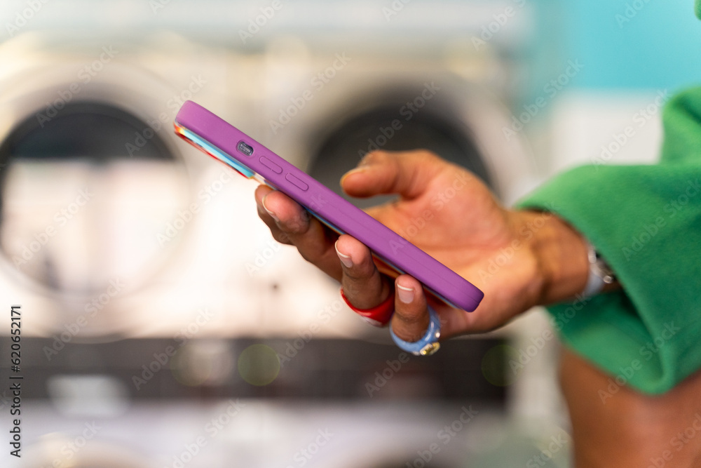 Hand holding smartphone at laundry