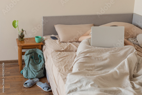 a man covered with a laptop lies in bed photo