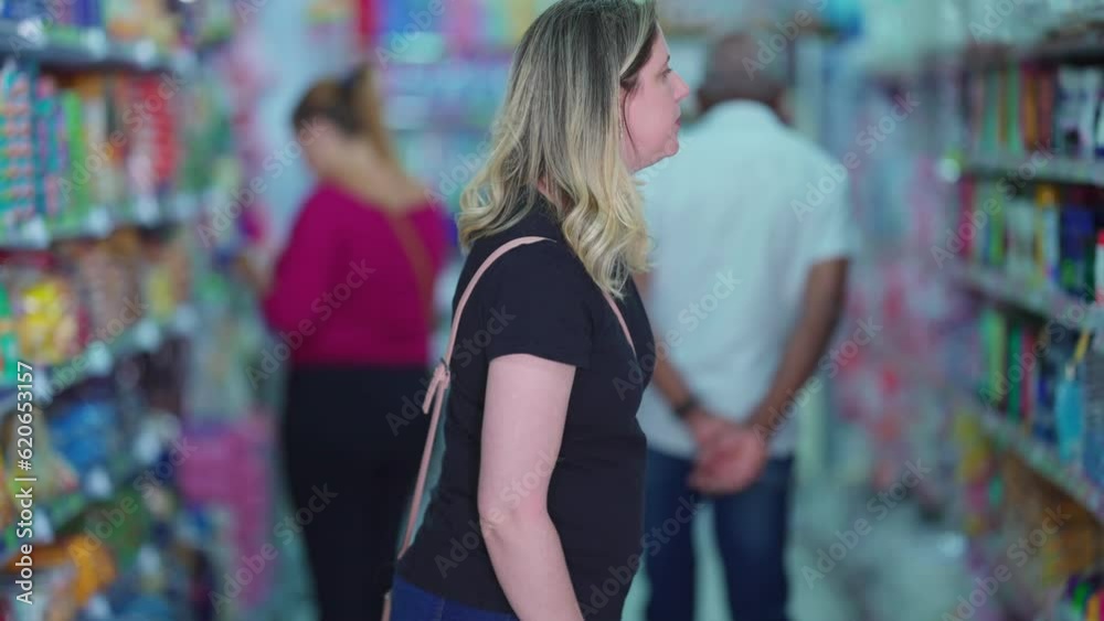 Grocery customers looking for products at aisle shelf searching for items to buy. Woman shopper browsing item goods, consumer lifestyle Grocery customers looking for products at aisle shelf searching for items to buy. Woman shopper browsing item goods, consumer lifestyle