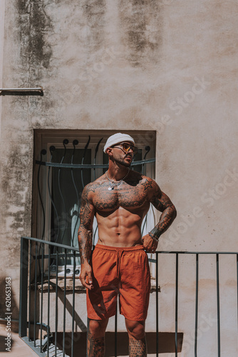 CHico joven musculado con tatuajes posando sin camiseta en piscina con estilo de hotel en día soleado  © MiguelAngelJunquera