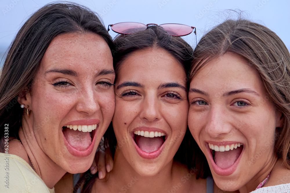 Headshot of three beautiful caucasian girls looking at camera excited. Close up of the faces of women friends together having a good time outdoors in a sunny day. Headshot of three beautiful caucasian girls looking at camera excited. Close up of the faces of women friends together having a good time outdoors in a sunny day.