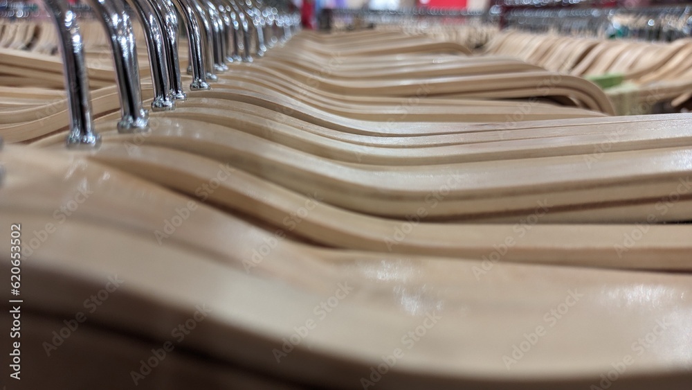 A lot of wooden hangers with a metal hook stand in a row in a clothing store