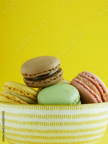 Macro, macarons of various flavors, typical French sweet. Yellow background and copy space.