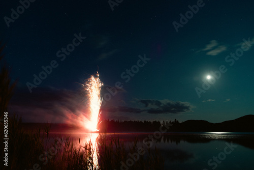 Φωτογραφία vue sur un lac avec des feux d'artifices au sol en train d'exploser la nuit avec