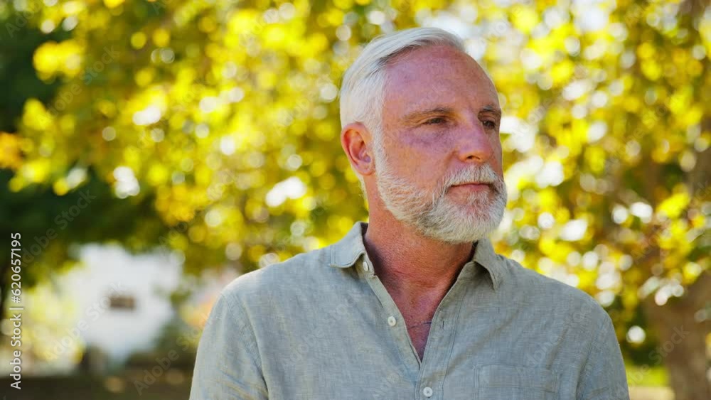 Portrait of smiling senior man folding arms outdoors in garden at home - shot in slow motion