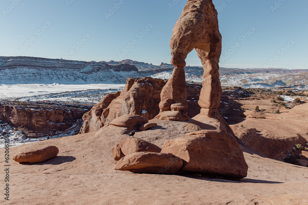 vue sur un rocher en forme d'arche en pierre rouge lors d'une journée ensoleillée d'hiver avec de la neige en arrière plan