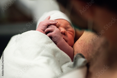 New born baby being held by dad after birth photo