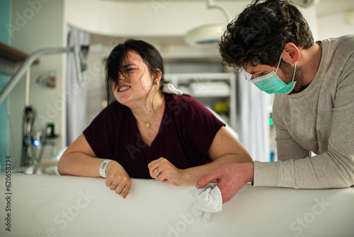 woman with contractions leaning on bath tub in hospital photo