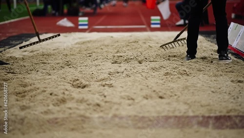 Close-up of Workers Raking the Long Jump Sand Pit. Leveling the Sand on Athletics Track after Jumps photo