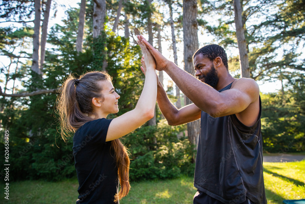 Two sportsmen during a workout in a public park give each other a high five