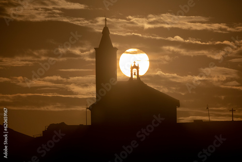 Sun aligned with the silhouette of the church of Luarca, Asturias, Spain photo