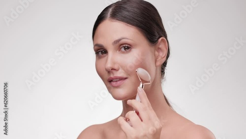 Close up portrait adorable half-naked woman. Beauty and skin care. Female using natural massager tool for skin care and spa beauty treatment. Young woman using jade facial roller for face massage.