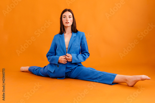 Stylish woman sitting on floor with stretched legs