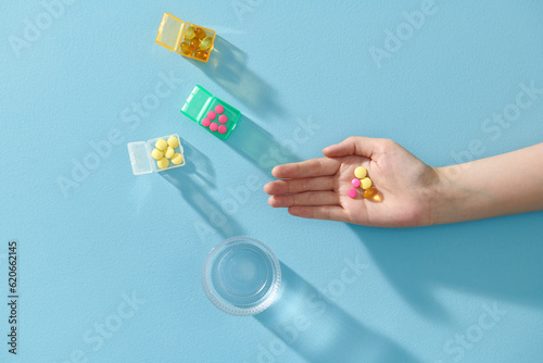Close-up shot of a hand holding color pills on blue background. photo