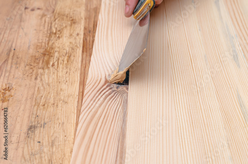 Billede på lærred Covering knots on a wooden board with putty