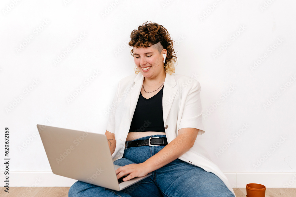 Smiling gender fluid person working on laptop Smiling gender fluid person working on laptop