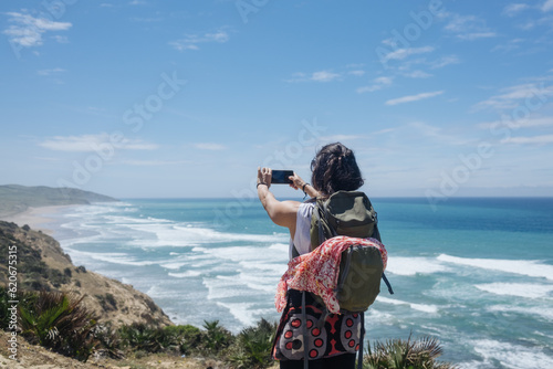 Tourist woman photographing a beach with her mobile phone